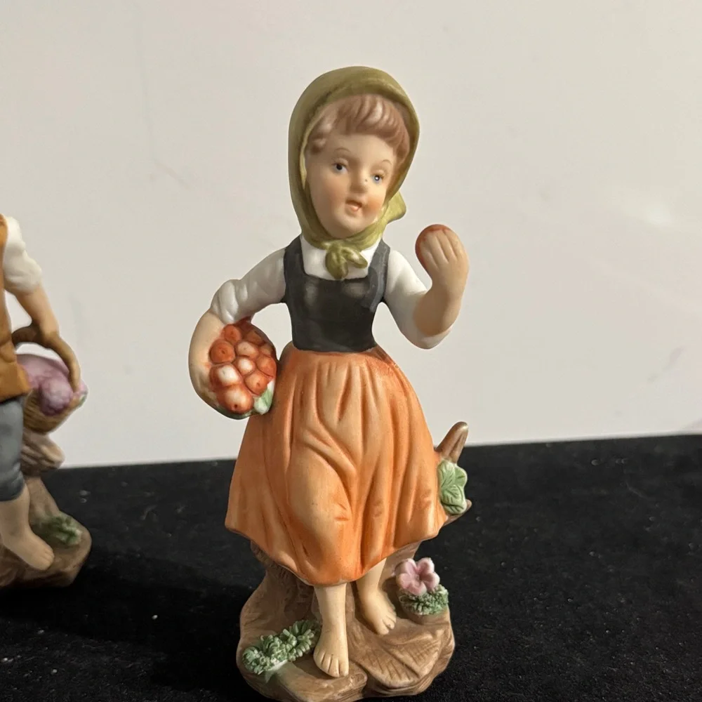 vintage hand-painted porcelain figurines of a boy and girl carrying baskets.